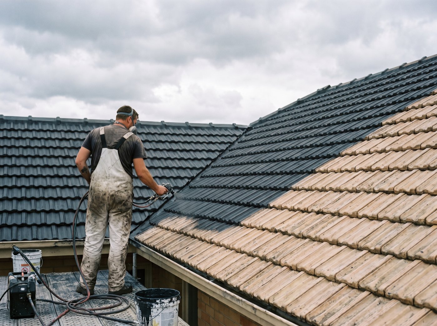Charcoal roof membrane being sprayed onto cleaned tiles